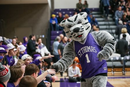 The University of St. Thomas mascot, Tommie, giving high fives at a basketball game, 2023.